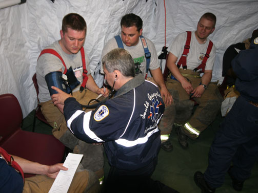 South Orangetown Ambulance Corps member Stephen Harris checks fire fighters' vitals during a brief break in the DRASH rehab shelter.