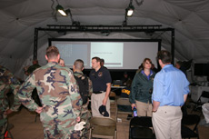 OCME and military personnel meet inside the DRASH J Shelter equipped with a Large Screen Display.